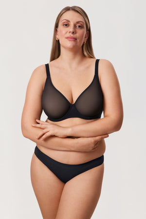 Woman wearing a black bra and underwear set on a plain background